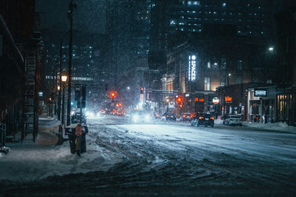 A snowy city street at night with people walking