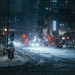 A snowy city street at night with people walking