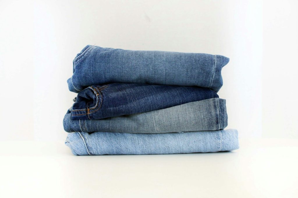 A neat stack of folded jeans on a white background