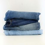 A neat stack of folded jeans on a white background
