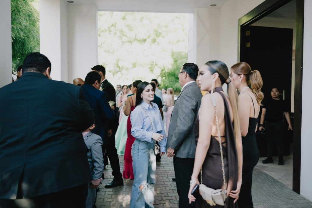 Wedding guests in suits and dresses gathering at a venue entrance
