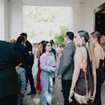 Wedding guests in suits and dresses gathering at a venue entrance